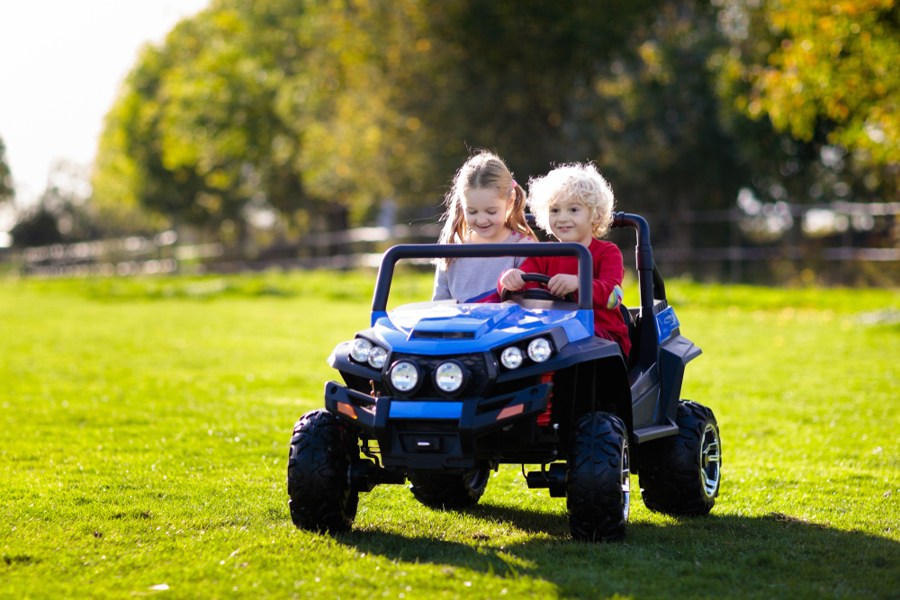 Two girls driving an electric car on the grass