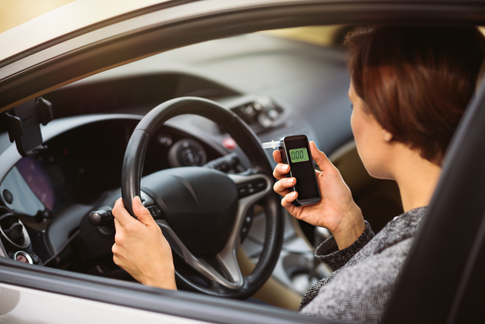 woman using breathalyzer in car