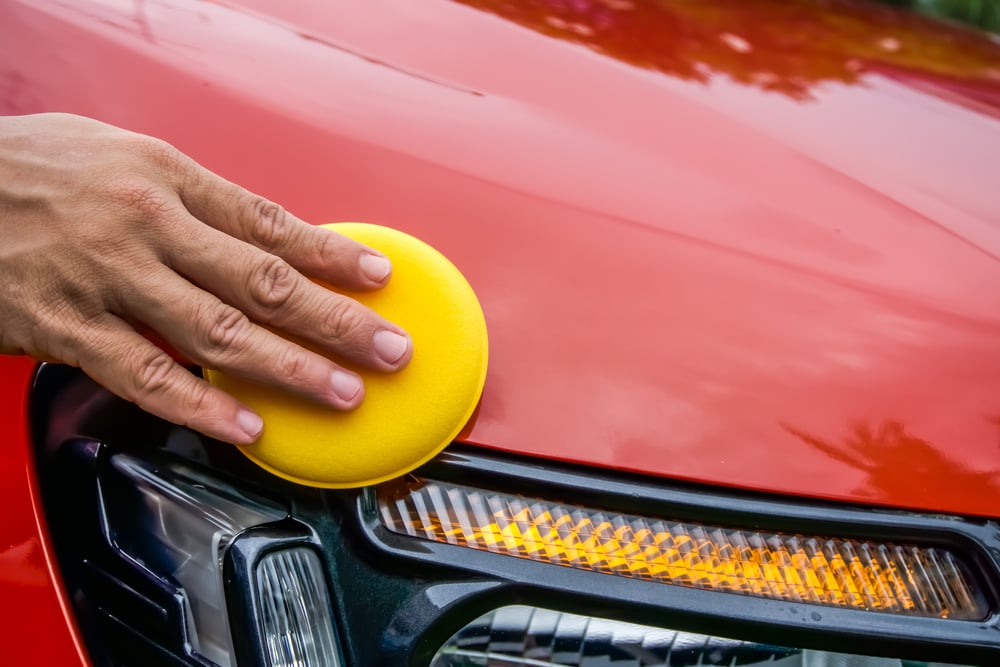 hand waxing car with yellow pad