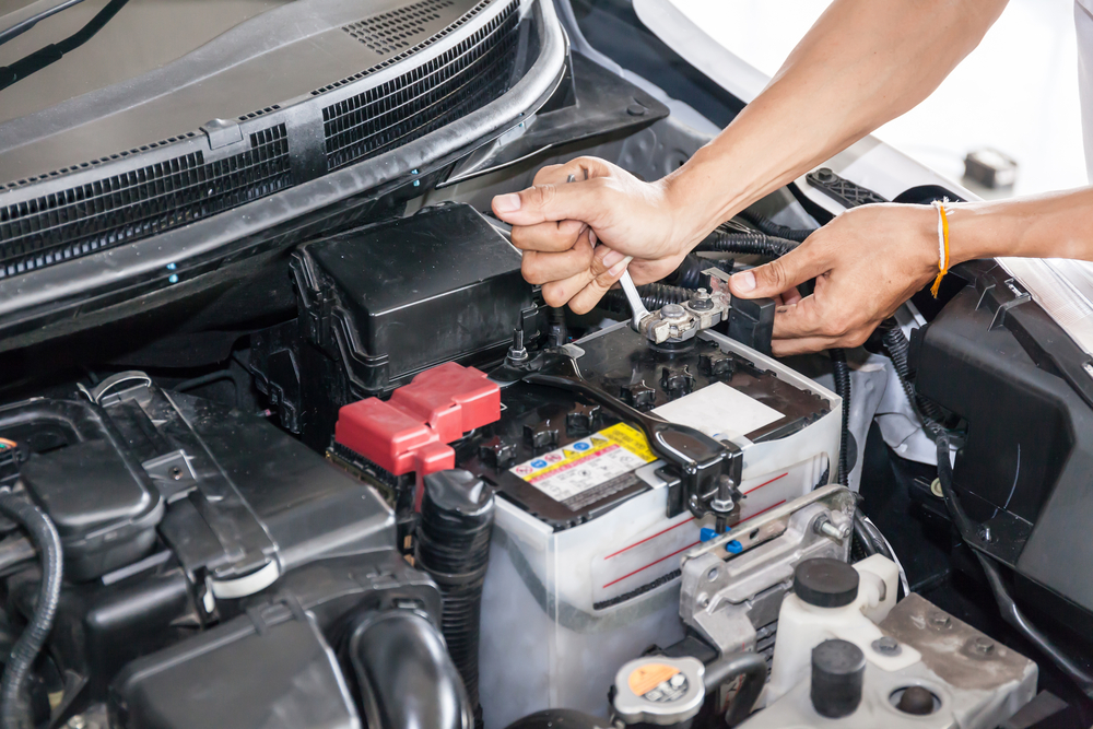 mechanic changes a vehicle battery