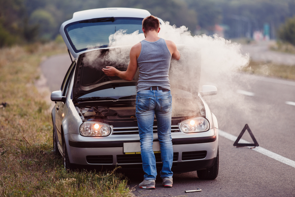 driver attends to smoking car hood