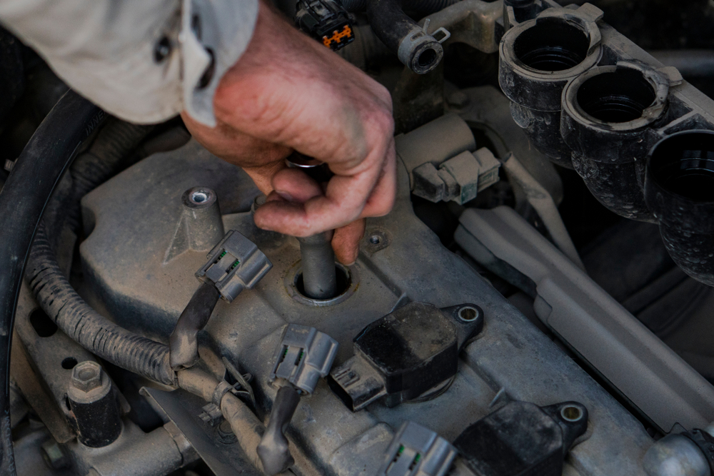 a man is replacing the spark plug in his car’s engine