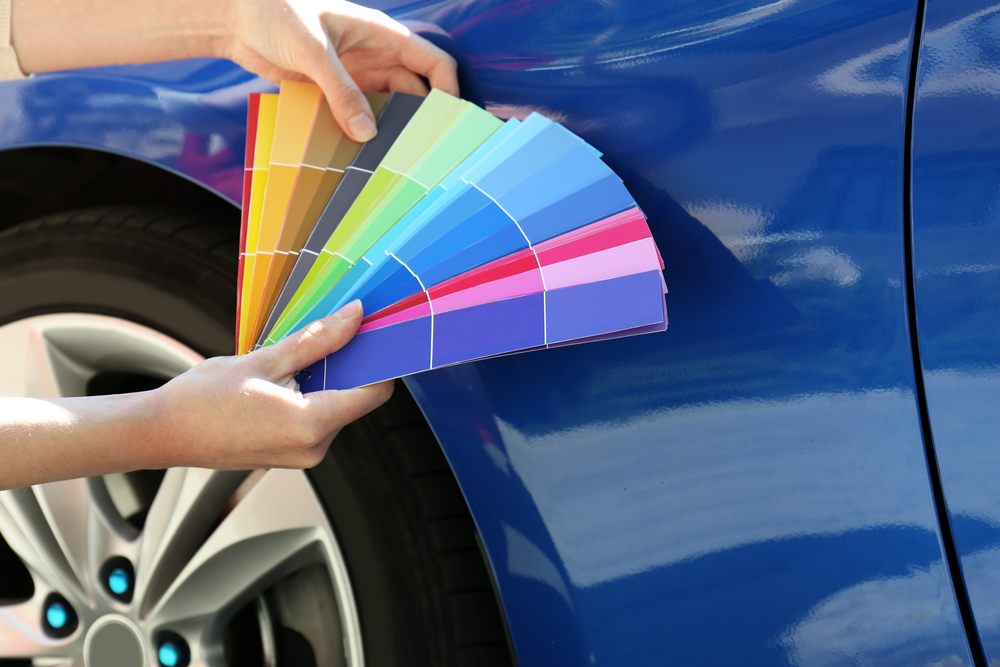 holding color samples up to a car