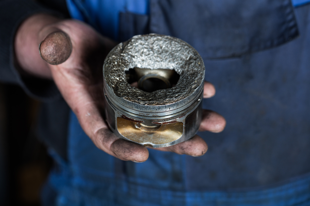 mechanic holding a damaged piston