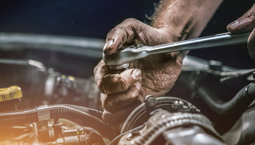 mechanic using a ratchet on engine