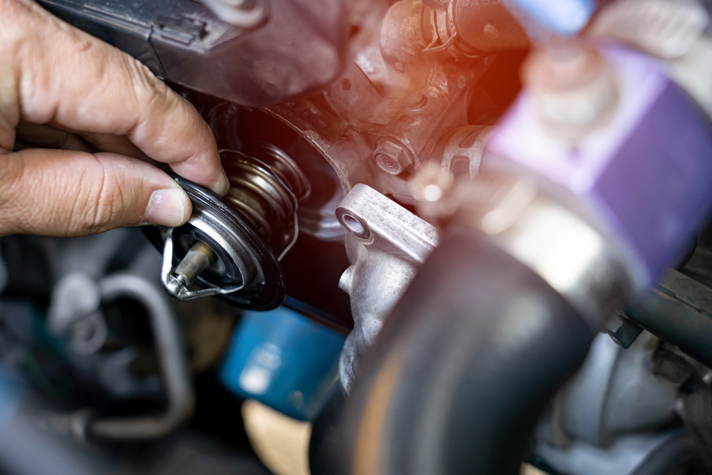 thermostat being removed from the top of an engine