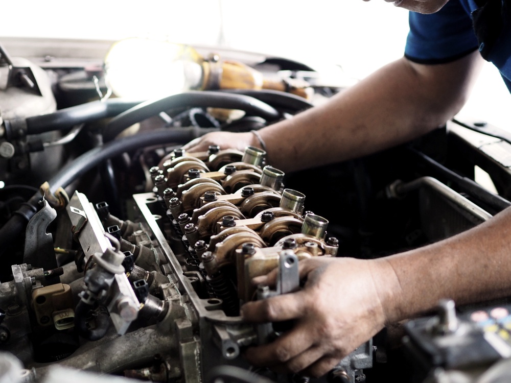 a mechanic working on the head of an engine