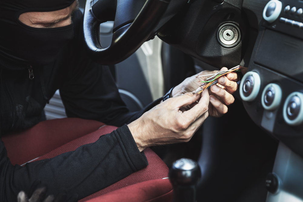 masked man fiddling with exposed steering wheel wires