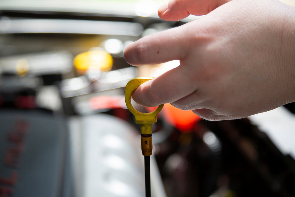 checking transmission fluid in car by lifting yellow dipstick