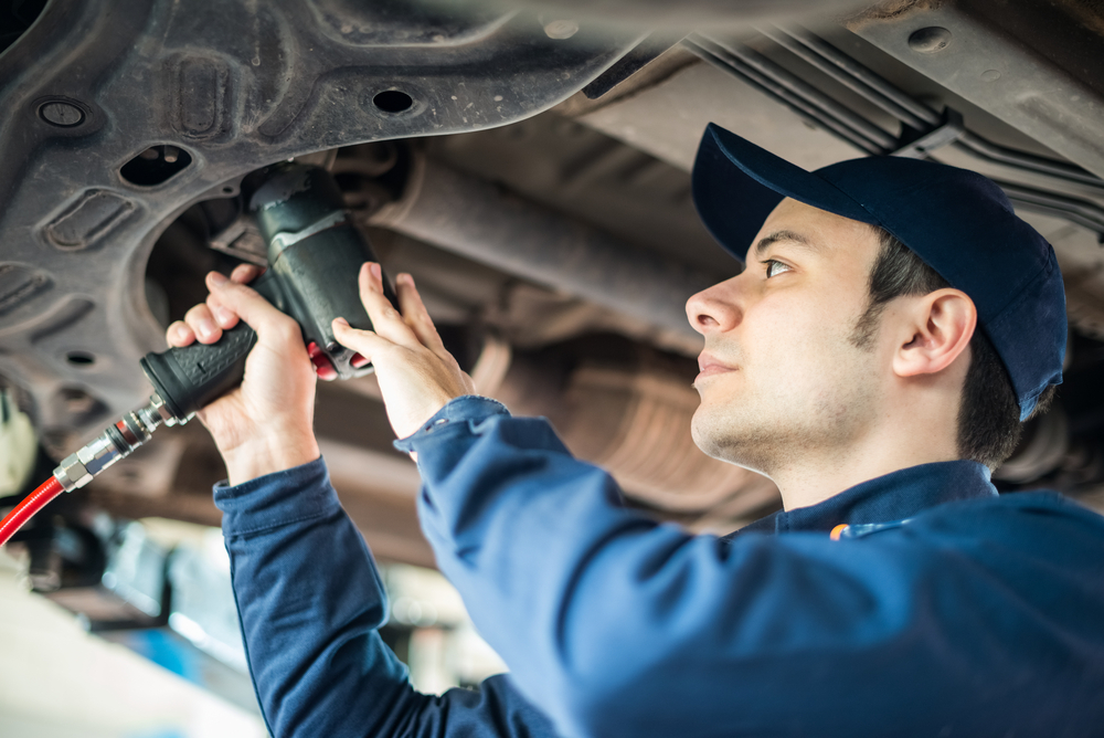 man uses air tools underneath a vehicle