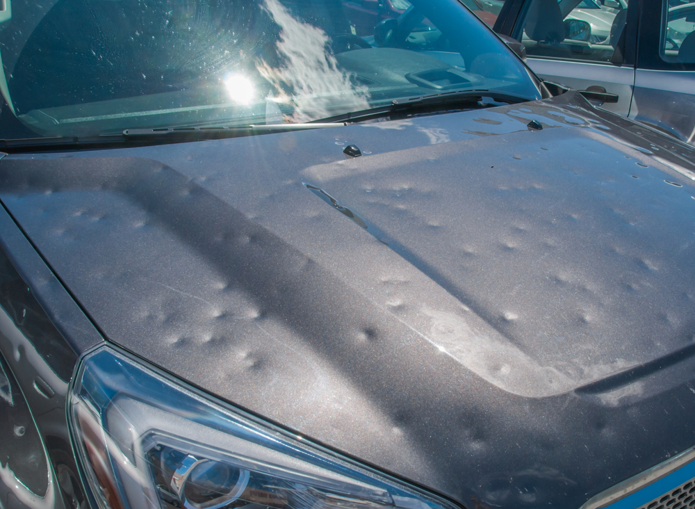 a vehicle hood full of small round dents from hail