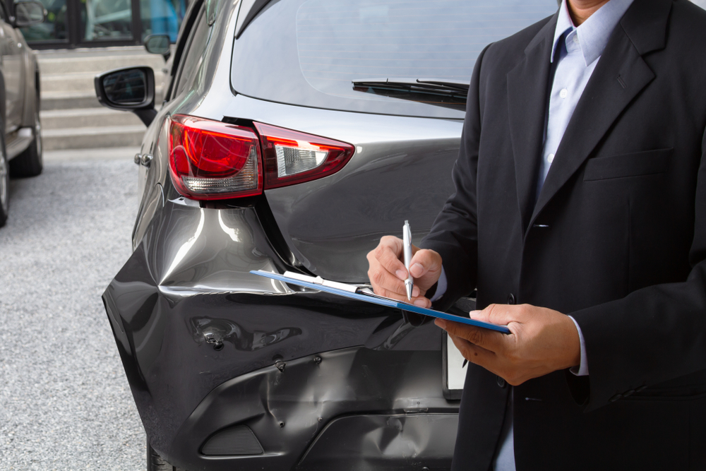 insurance officer looking at rear bumper damaging