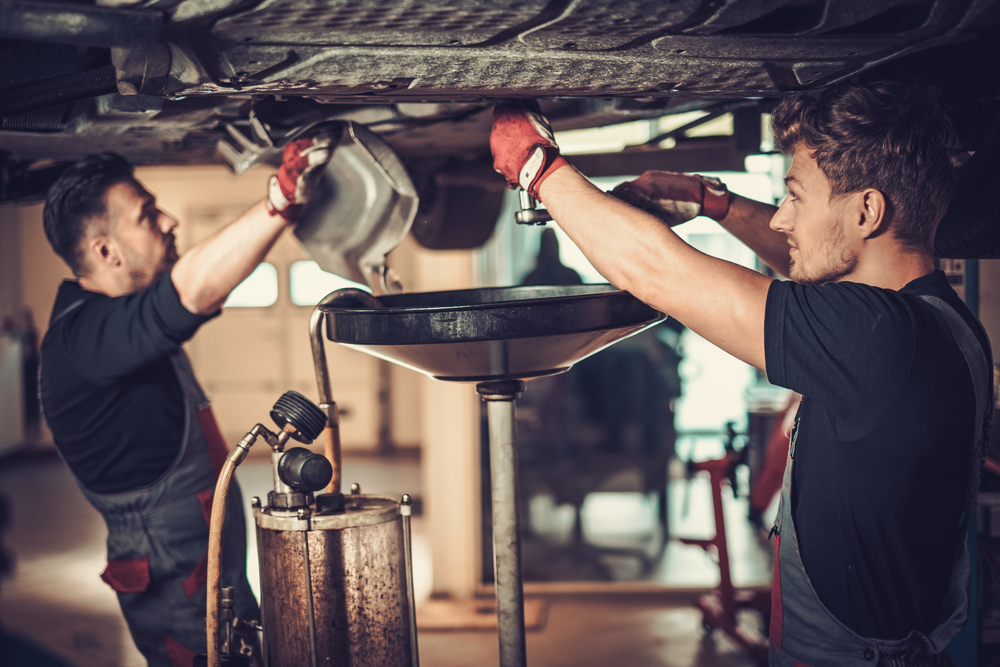 technicians changing the oil in a car