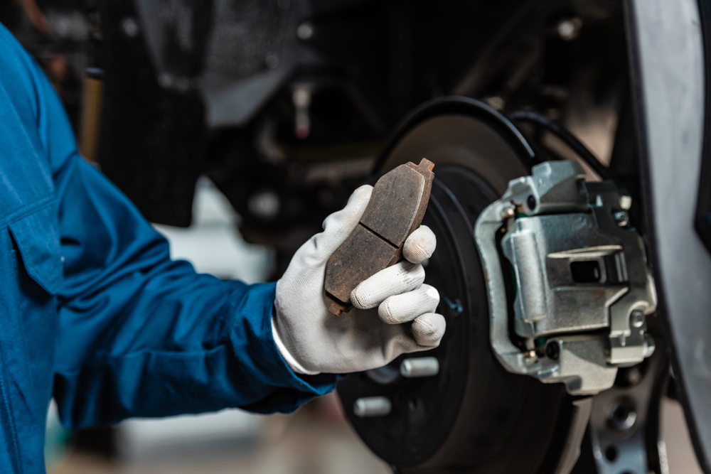 car mechanic looking at a brake pad