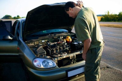 man looking at the engine of car